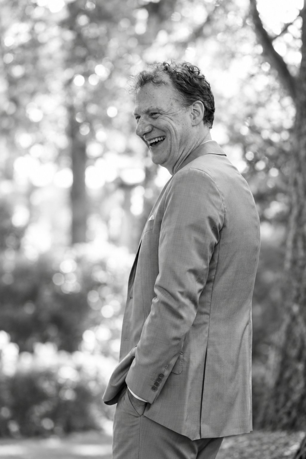Ingo laughing in a light suit in a sunlit garden